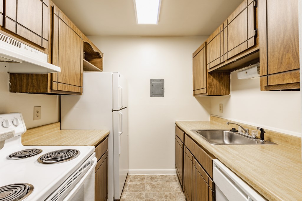 A kitchen with wooden cabinets and a white stove top oven