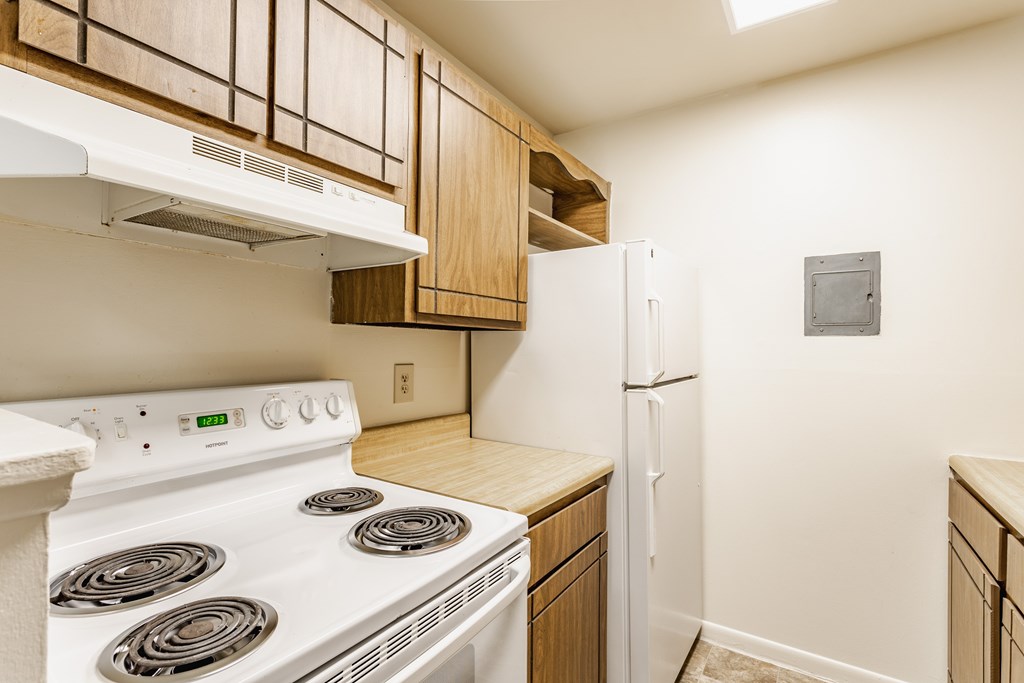 A white stove and refrigerator in a kitchen with wooden cabinets