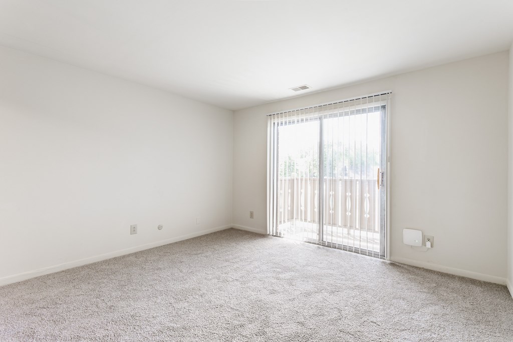 A room with a carpeted floor and a sliding glass door