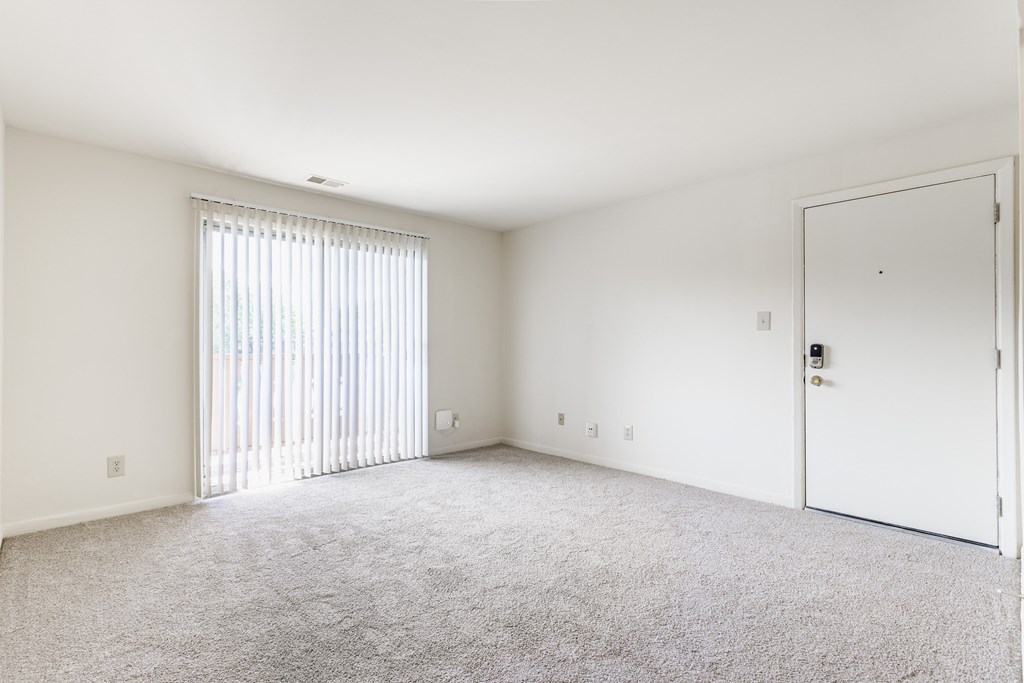 A room with a carpeted floor and a sliding glass door