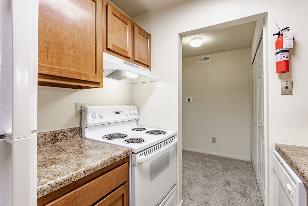 A kitchen with a white stove and wooden cabinets