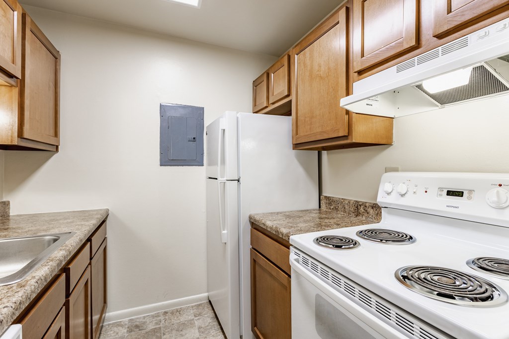 A kitchen with a white stove and a white refrigerator