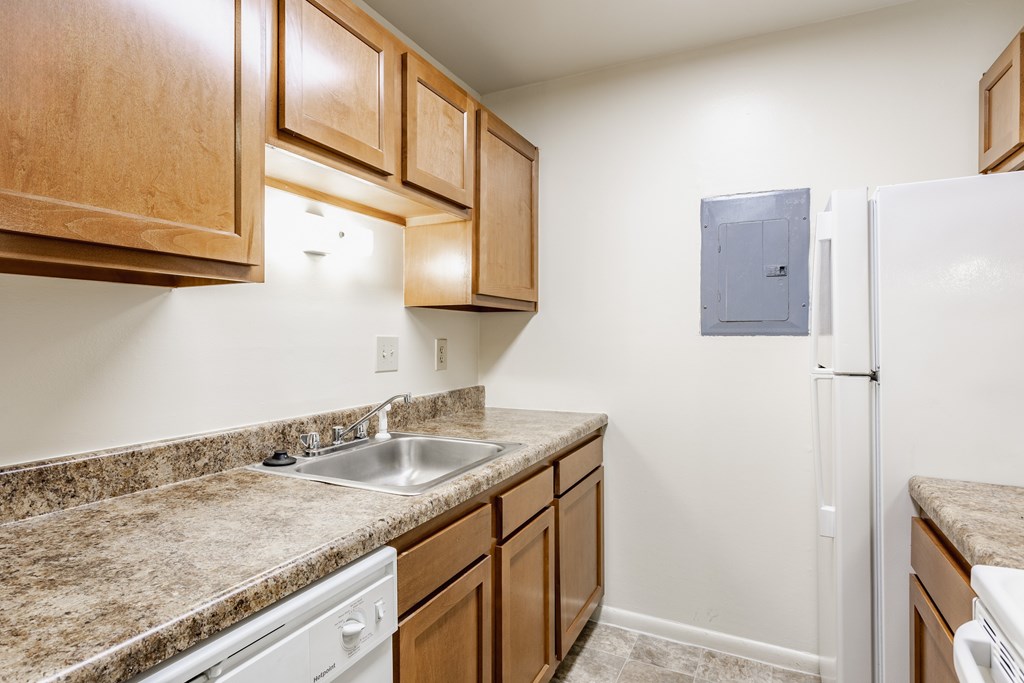 A kitchen with a white fridge and brown cabinets