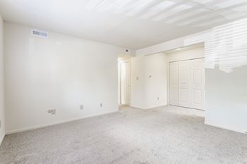 A spacious room with white walls and carpeted floor
