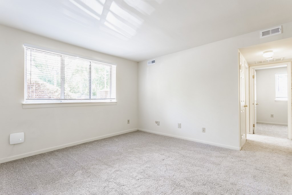 A room with a carpeted floor and a window letting in natural light