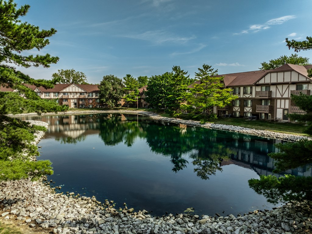 a large pond in front of a building with trees