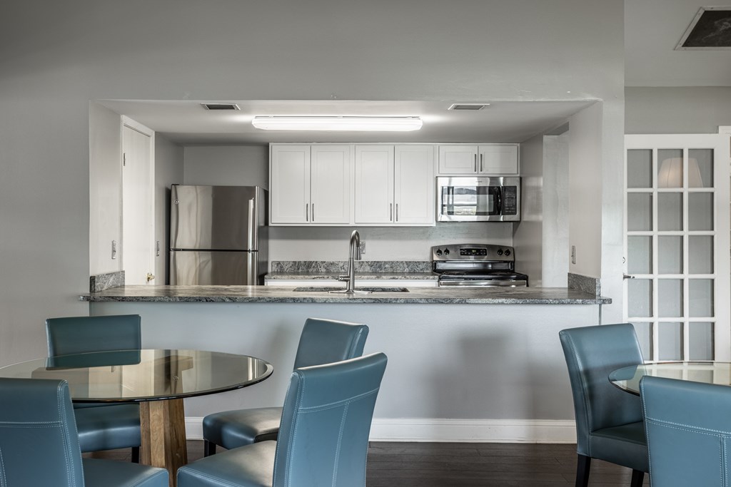 A modern kitchen with a glass table and blue chairs