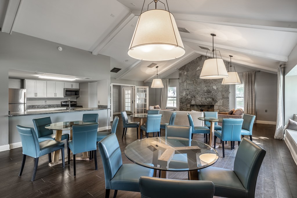 A modern dining room with a glass table surrounded by blue chairs