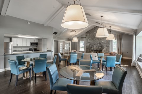 A modern dining room with a glass table surrounded by blue chairs