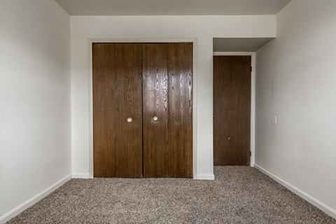 a bedroom with two closet doors and a carpet floor at Bay Pointe Apartments in Lafayette, IN 47909