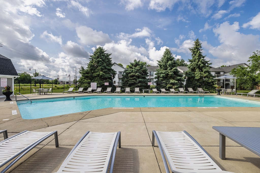 A pool surrounded by trees and chairs
