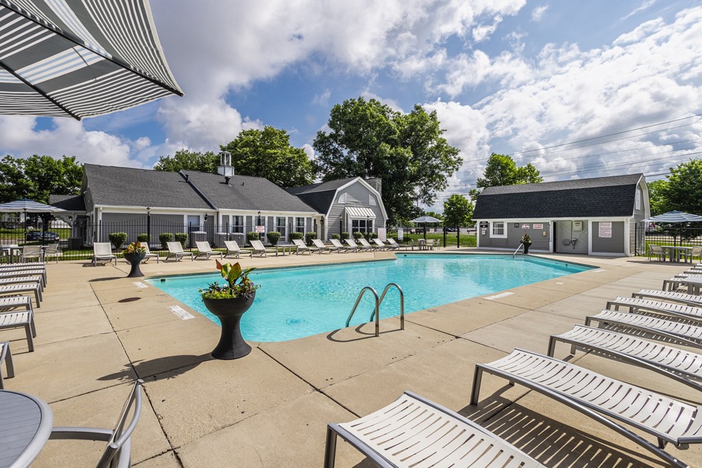 A pool area with sun loungers and a building in the background