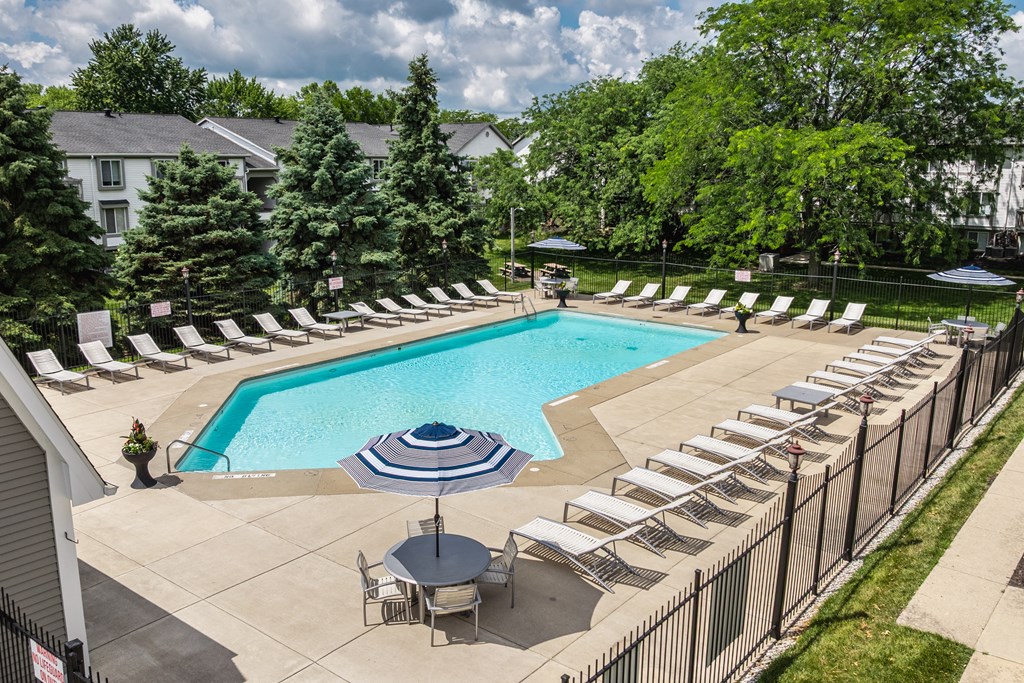A pool surrounded by chairs and trees