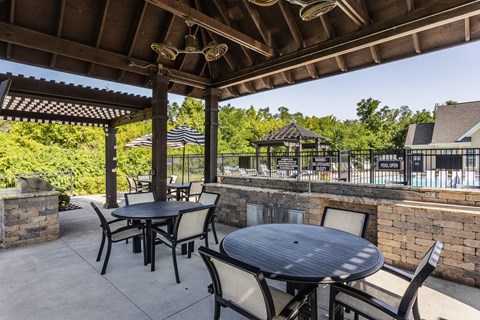 an outdoor patio with tables and chairs and a pool at Bella Vista Apartments, Fishers, IN, 46038