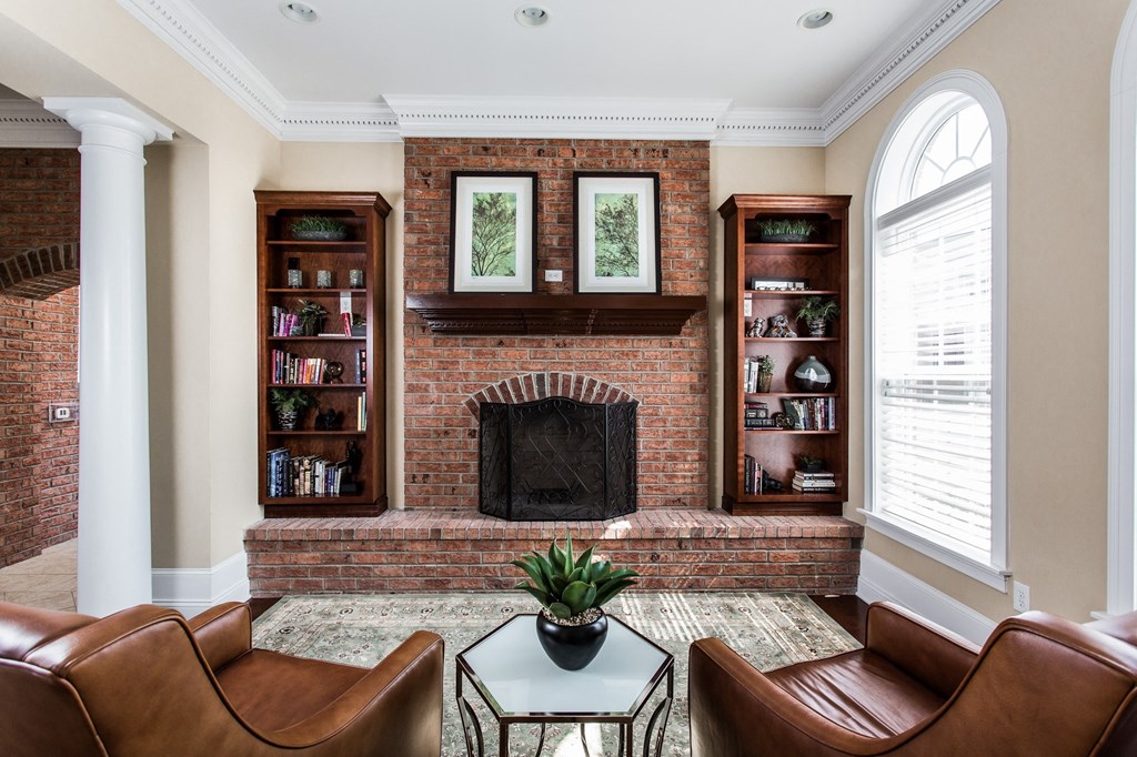 a living room with a brick fireplace and leather furniture at Brickshire Apartments, Merrillville, IN