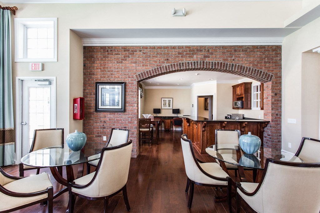 a dining room with a table and chairs and a brick wall at Brickshire Apartments, Merrillville, IN, 46410