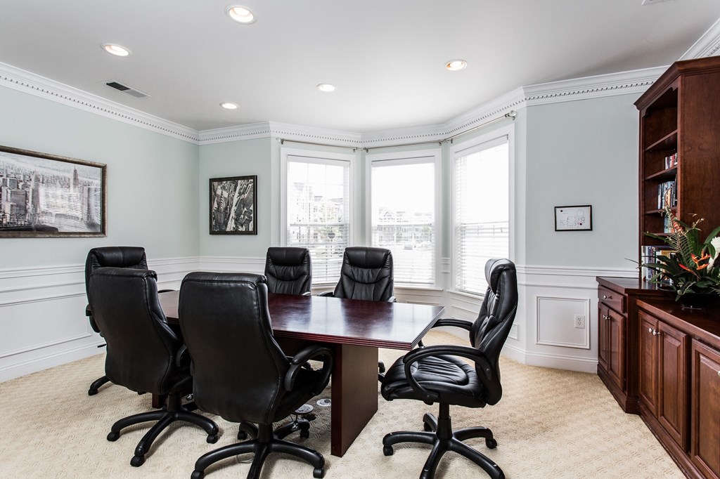 a conference room with a wooden table and black chairs at Brickshire Apartments, Merrillville, IN