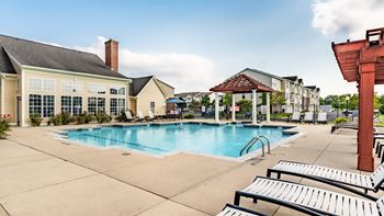 A pool area with sun loungers and a building in the background