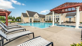 A pool area with sun loungers and a pavilion
