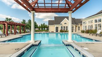 A large swimming pool with a wooden pergola over it
