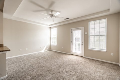 A spacious room with a ceiling fan and carpeted floor
