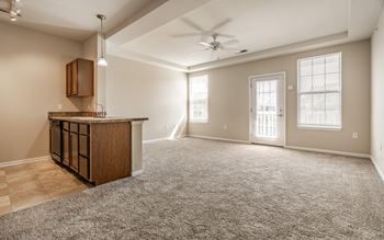 A spacious living room with a carpeted floor and a ceiling fan