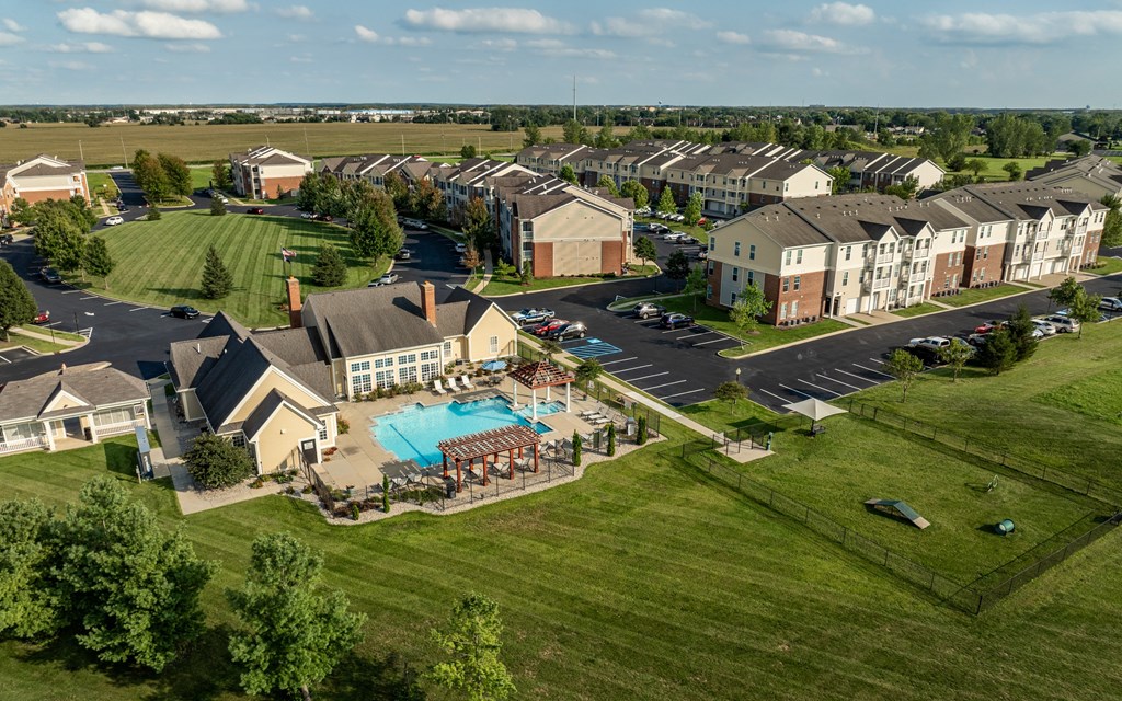 A large grassy area with a swimming pool and apartment buildings in the background