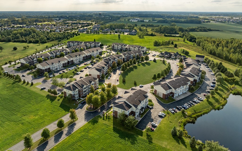 A bird's eye view of a housing complex with a lake in the foreground