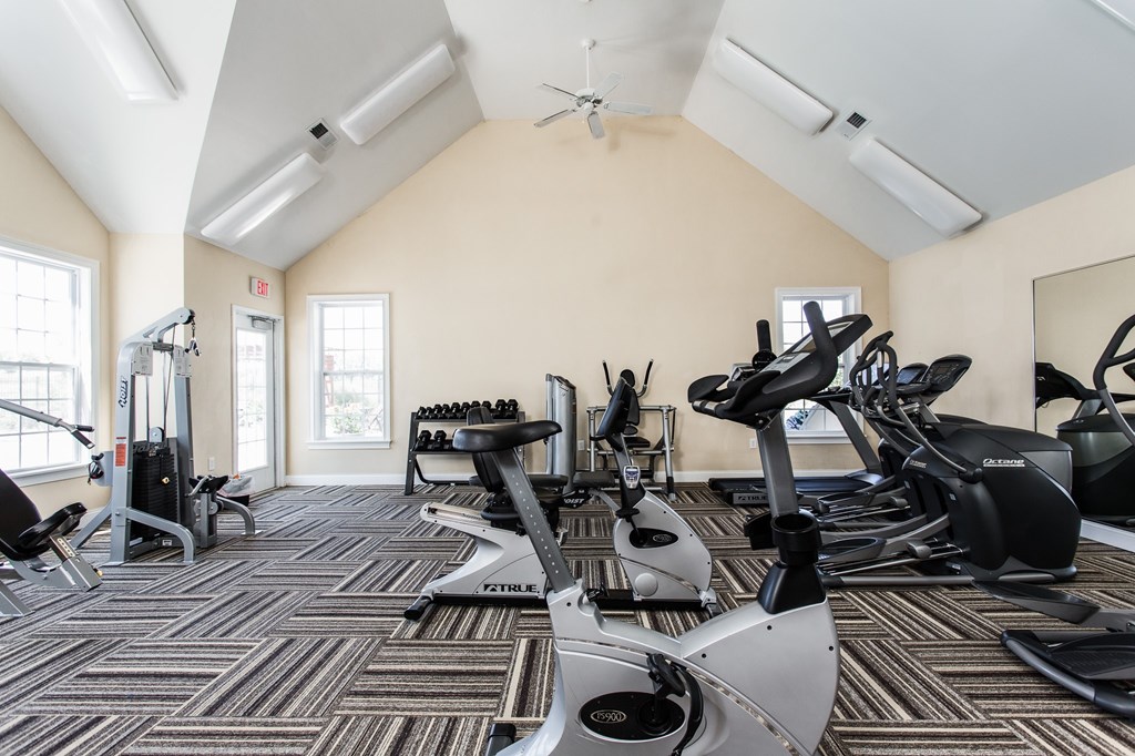 A gym with a variety of exercise equipment including treadmills, stationary bikes, and elliptical machines