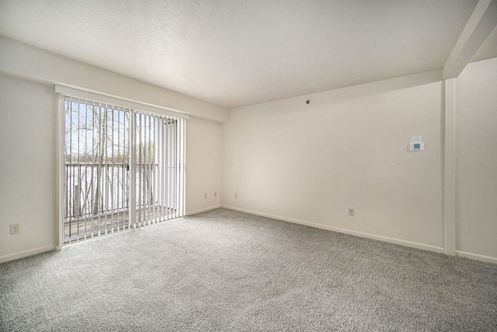 an empty living room with a sliding glass door to a balcony at Canal 2 Apartments in Lansing, MI