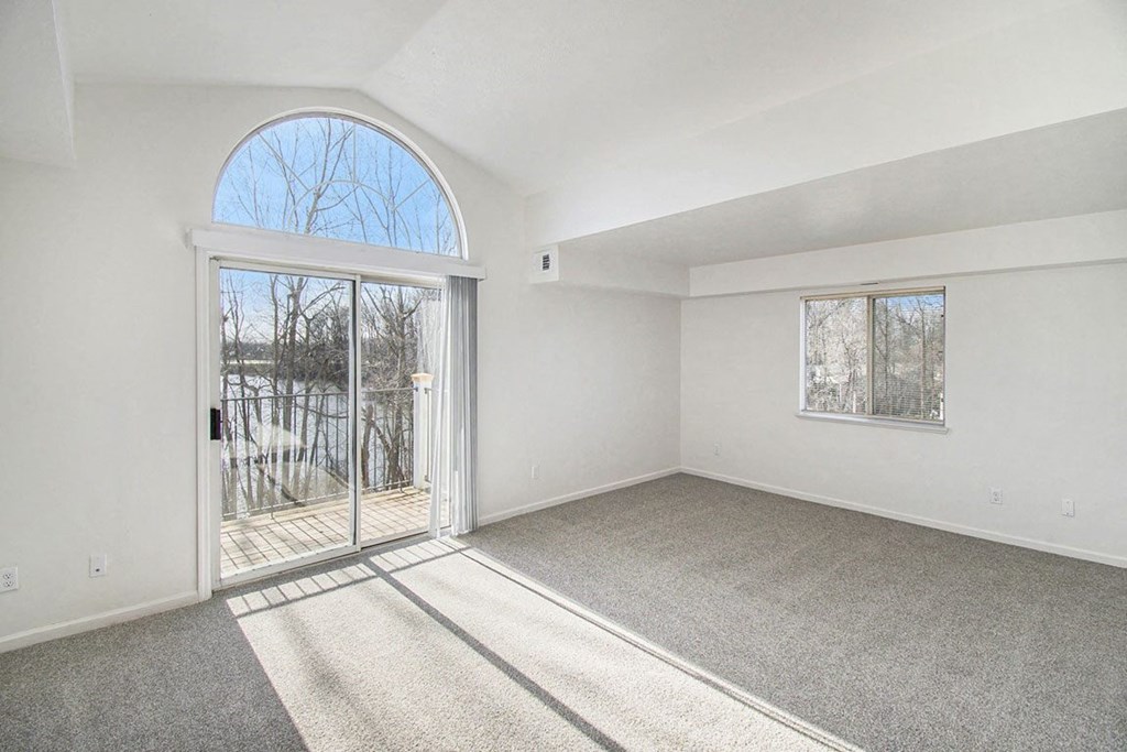 Enlarged living room with a cathedral ceiling and door to a balcony at Canal 2 Apartments, Lansing, Michigan