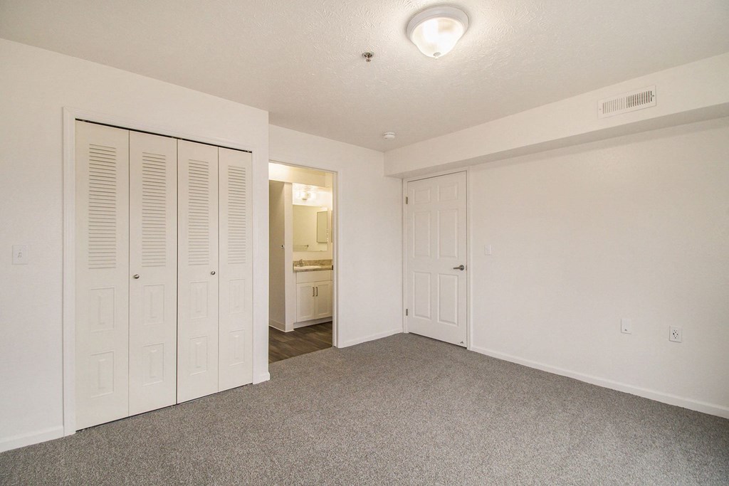 an empty bedroom with spacious closets and a carpeted floor at Canal 2 Apartments, Lansing, Michigan