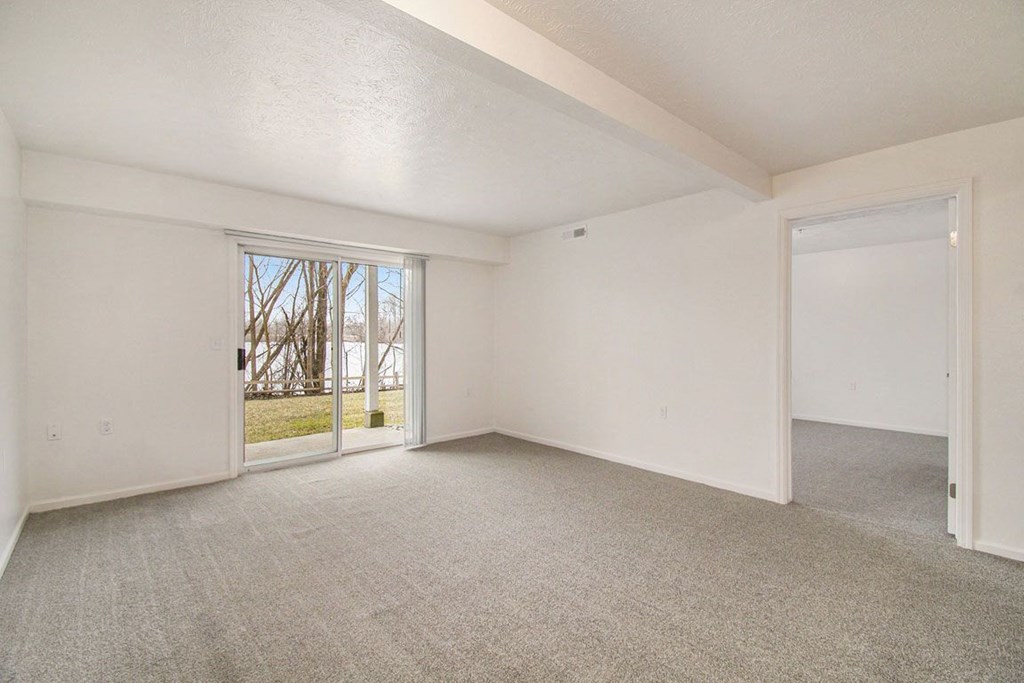 living room with a slider to a patio overlooking the landscaped grounds at Canal 2 Apartments in Lansing, MI