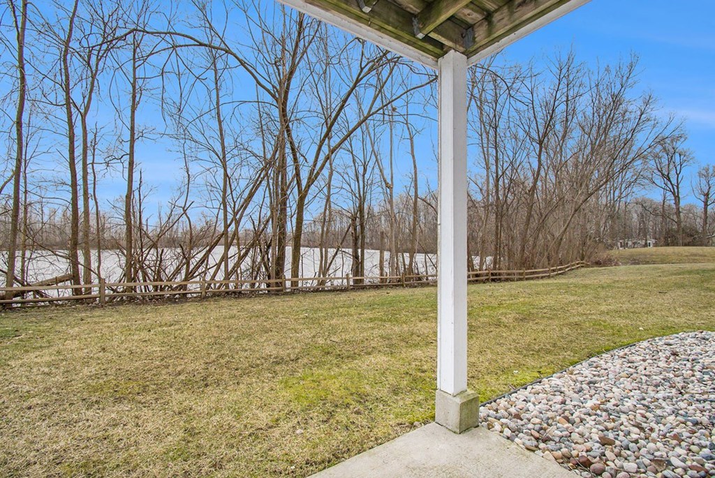 a private patio with a view of a pond and trees at Canal 2 Apartments, Lansing, Michigan