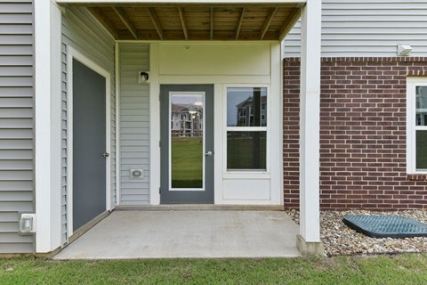 a front porch with a gray door and a red brick wallat Chase Creek Apartment Homes, Alabama