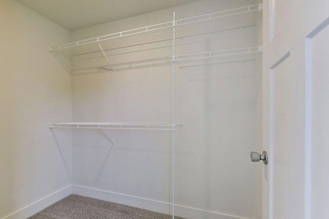 a walk in closet in a bedroom with white walls and a white door at Chase Creek Apartment Homes, Huntsville, 35811