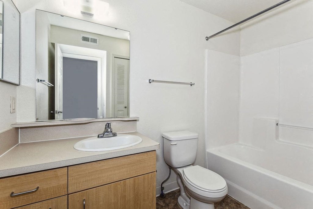 a bathroom with a sink toilet and a mirror at Colonial Pointe at Fairview Apartments, Bellevue, Nebraska