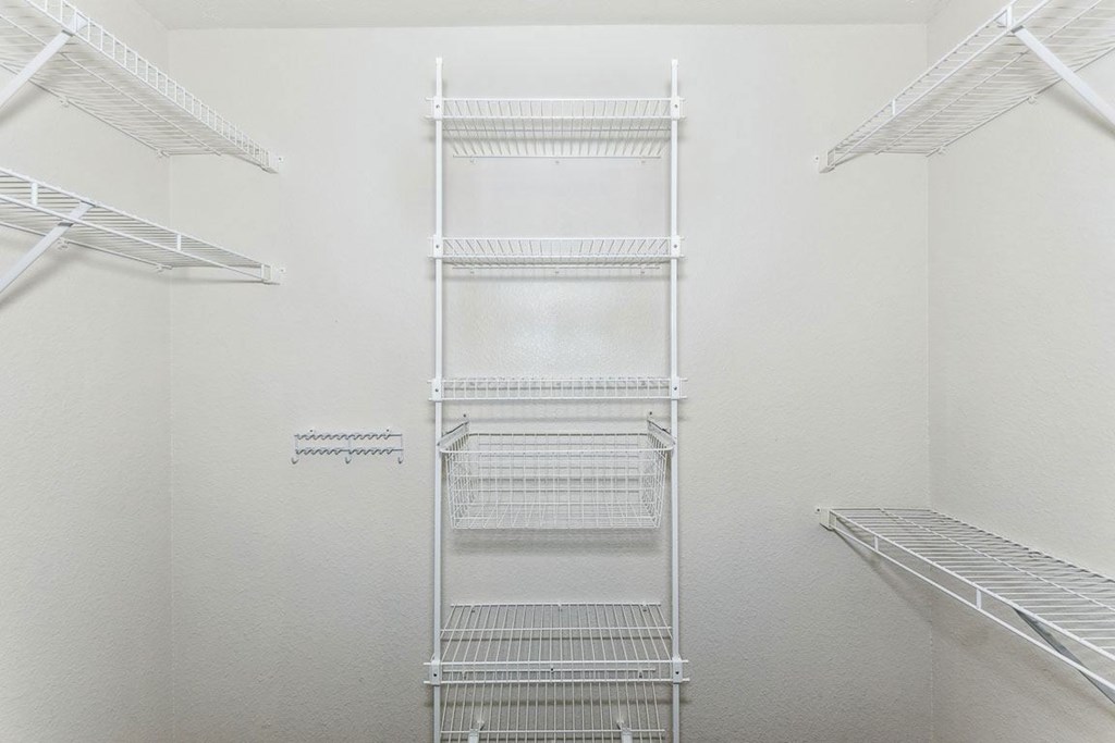 a walk in closet with white walls and white metal shelves at Colonial Pointe at Fairview Apartments, Bellevue, Nebraska