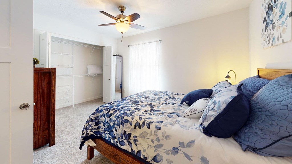 a bedroom with a large closet and a ceiling fan at Copper Creek Apartment Homes in Maize, Kansas 67101