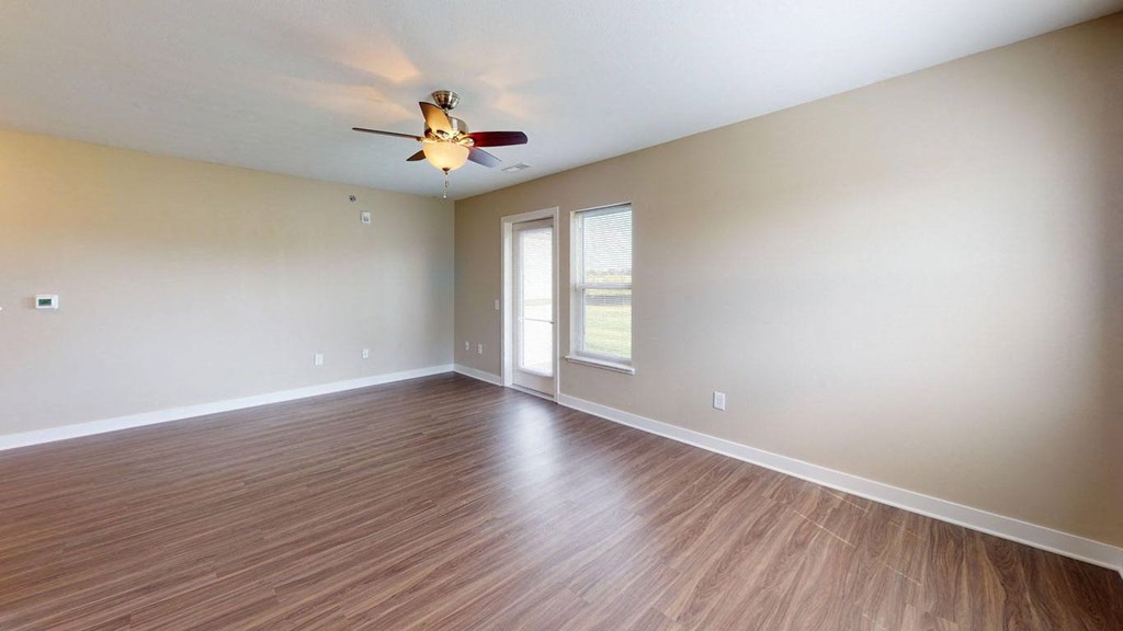 Enlarged living room with hard surface flooring and a ceiling fan at Copper Creek Apartment Homes in Maize, KS