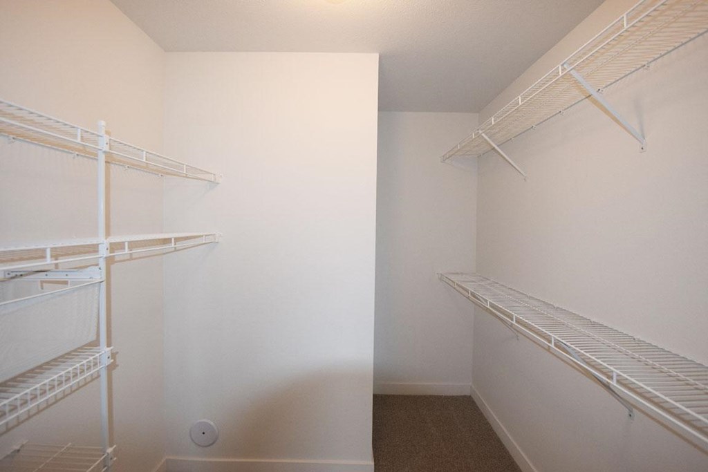 a walk in closet with wardrobe organizers at Copper Creek Apartment Homes in Maize, KS 67101