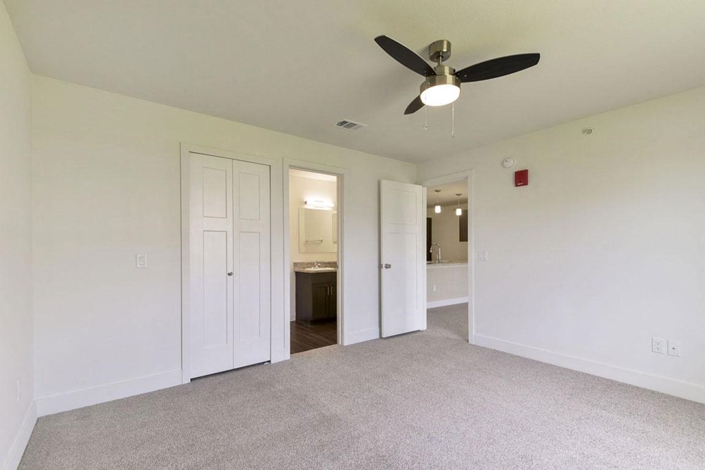 an empty bedroom with a ceiling fan and ensuite at Copper Creek Apartment Homes, Kansas, 67101