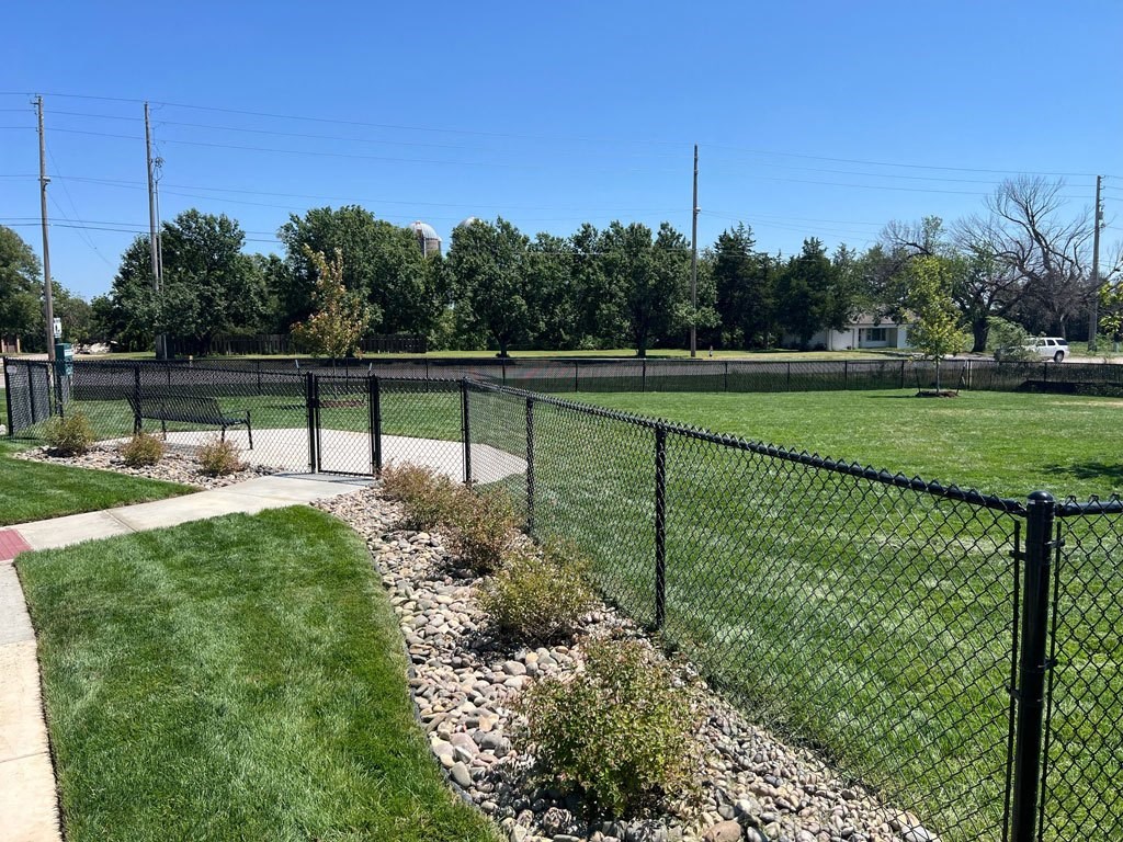 a dog park with a bench and fence at Copper Creek Apartments in Maize, KS