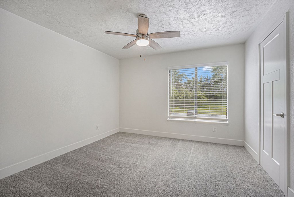 bedroom with a ceiling fan and a large window at The Crossings Apartments, Michigan, 49508