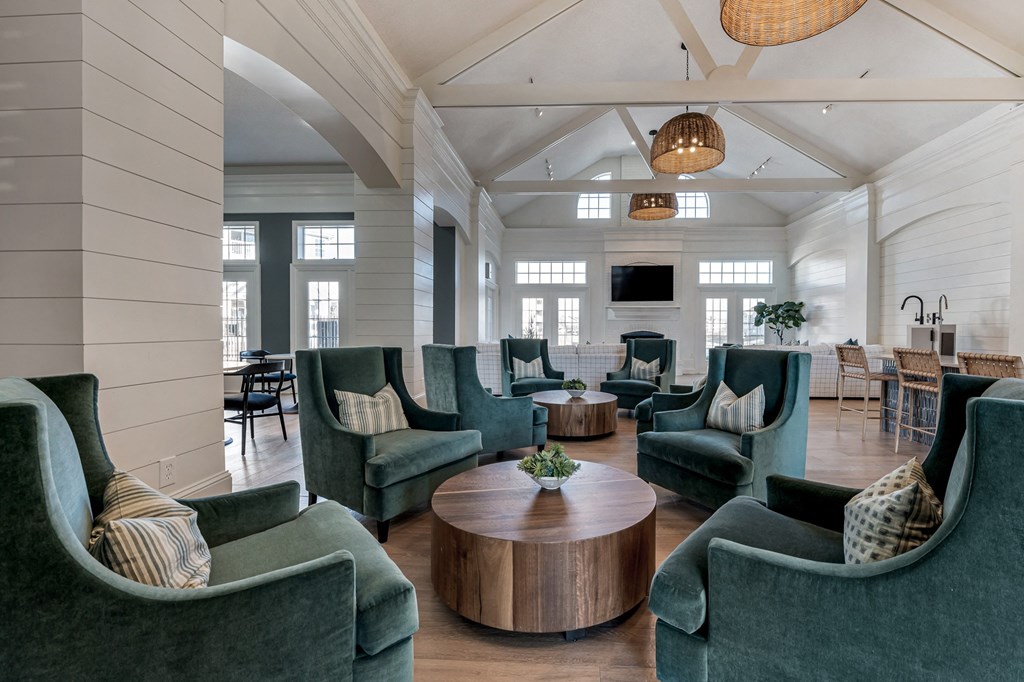 a large clubhouse lounge with green chairs and a table at Latitudes Apartments, Indianapolis, IN, 46237