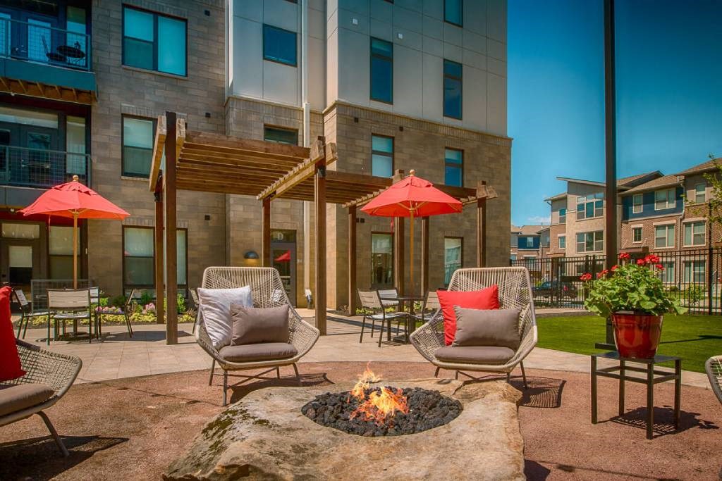 a fire pit in the middle of a patio with chairs and umbrellas  at Avant & Avant II, Carmel, IN