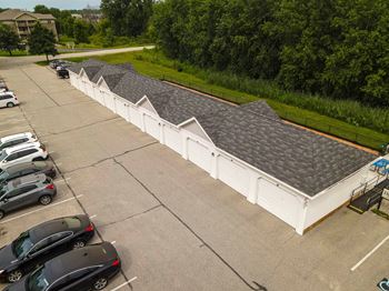 A parking lot with cars and a white building with grey roofs.