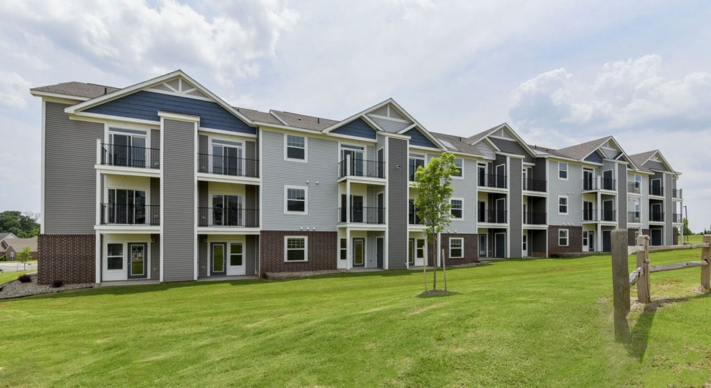 an image of an apartment building with a green lawn at Dodson Pointe Apartment Homes, Rogers, AR, 72758