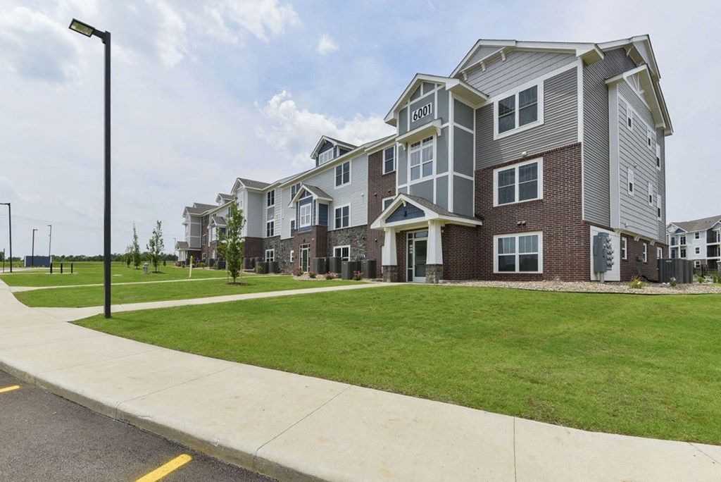 the outlook of a row of apartment buildings with green grass and sidewalks at Dodson Pointe Apartment Homes, Rogers, AR, 72758