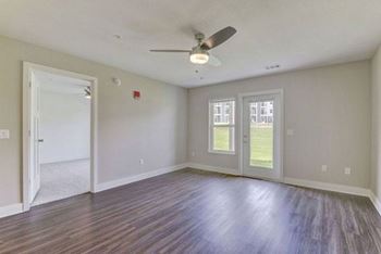 an empty living room with a ceiling fan and hard surface flooring at Dodson Pointe Apartment Homes in Rogers, AR